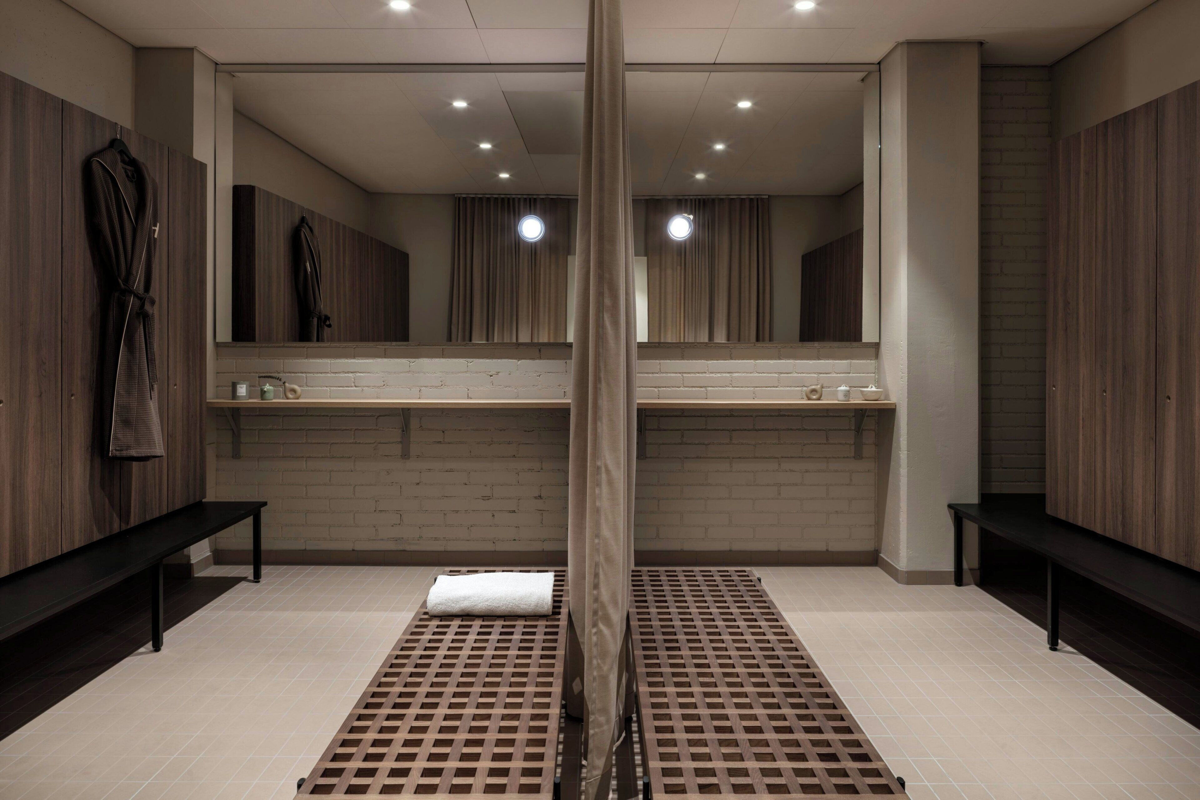 Un baño moderno con paneles de madera, un espejo grande y un banco.