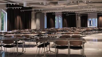 Un salón de conferencias amplio con filas de mesas y sillas, ventanas grandes y un diseño moderno en el techo.