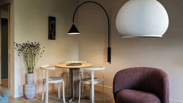 Un salon moderne avec une table ronde, quatre chaises, un grand lampadaire, un grand lustre et une plante en pot.