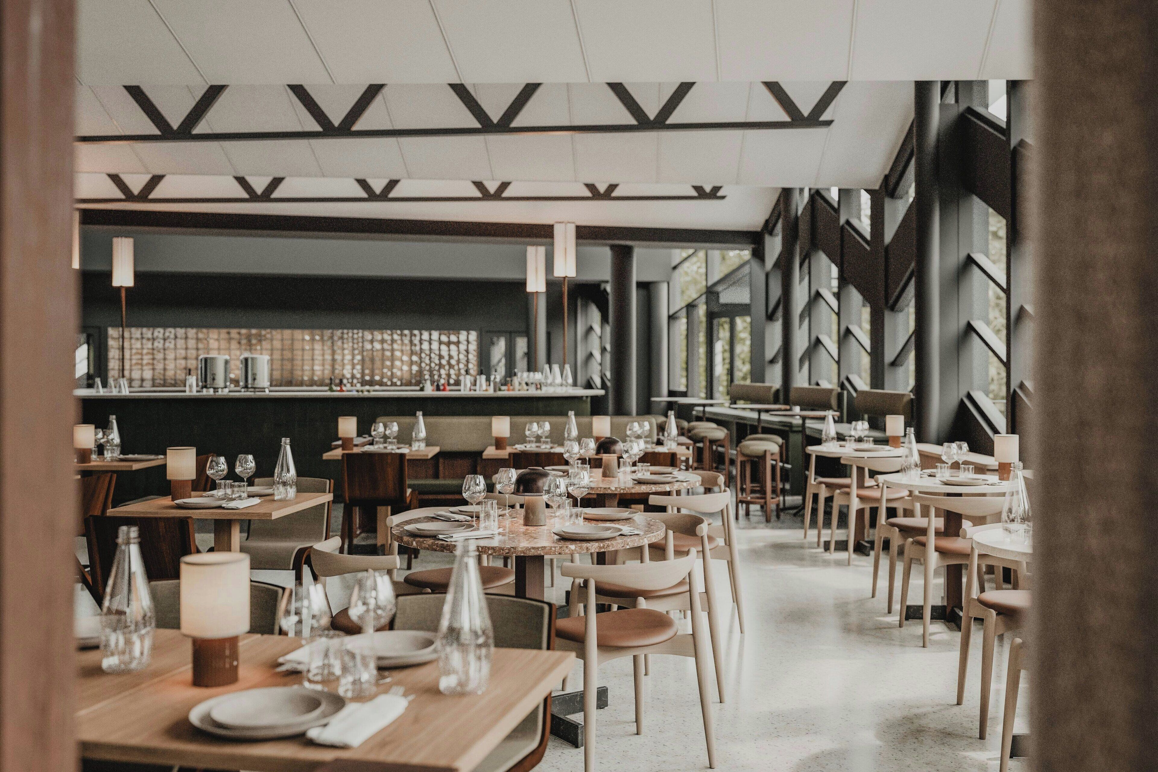 Un restaurant avec des tables rondes, des chaises et un coin bar.