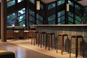 Zona de bar con ventanas altas, taburetes de madera y un salpicadero de azulejos.