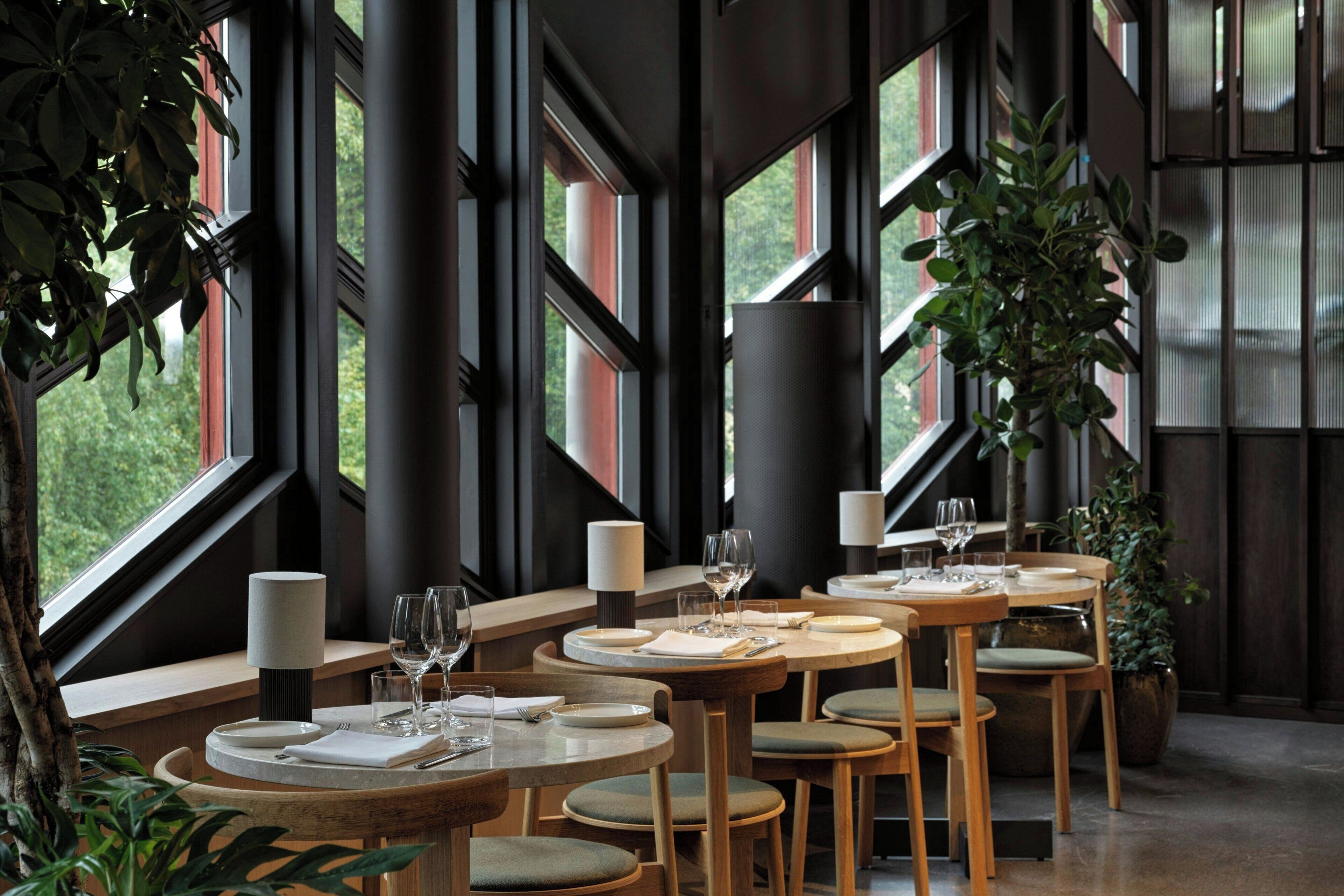 Un restaurant avec des tables rondes, des chaises et des plantes en pot.