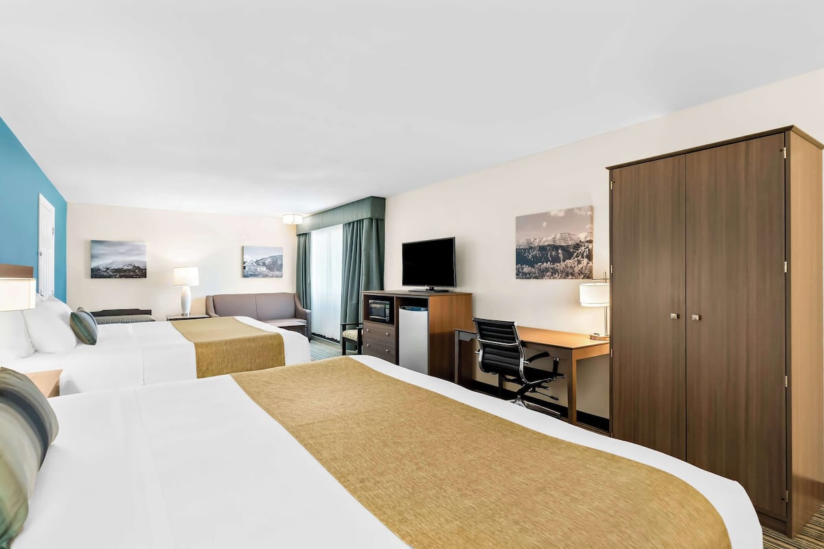Une chambre d’hôtel avec deux lits, un bureau, une télévision et une armoire.