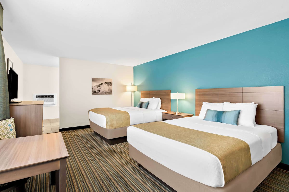Une chambre d’hôtel avec deux lits, un bureau et une chaise.
