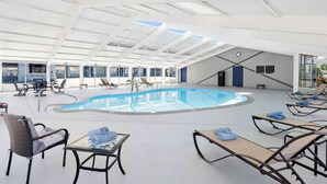 An indoor swimming pool with lounge chairs and tables, large windows, and a high ceiling with skylights. - Best Western Paradise Inn Of Nephi (Nephi)