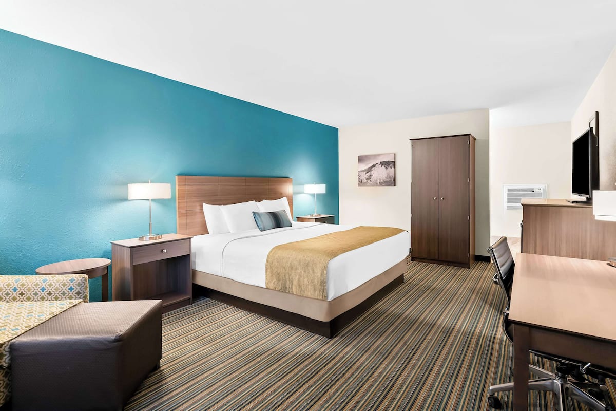 Une chambre d’hôtel comprenant un lit, des tables de chevet, un bureau, une chaise et une armoire.