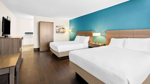 A hotel room with two beds, a desk, a TV, and a bathroom. - Best Western Paradise Inn Of Nephi (Nephi)