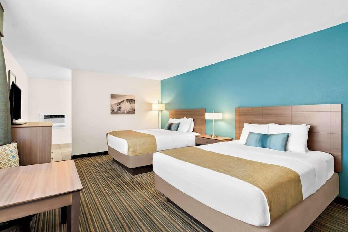Une chambre d’hôtel avec deux lits, un bureau et une chaise.