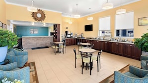 A spacious indoor area with a kitchen, dining tables, and chairs. There are potted plants and a large decorative mirror on the wall. - Best Western Paradise Inn Of Nephi (Nephi)