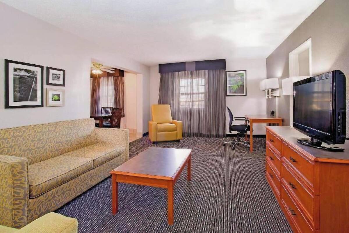Hotelkamer met een bank, fauteuil, televisie, houten dressoir en een klein tafeltje.