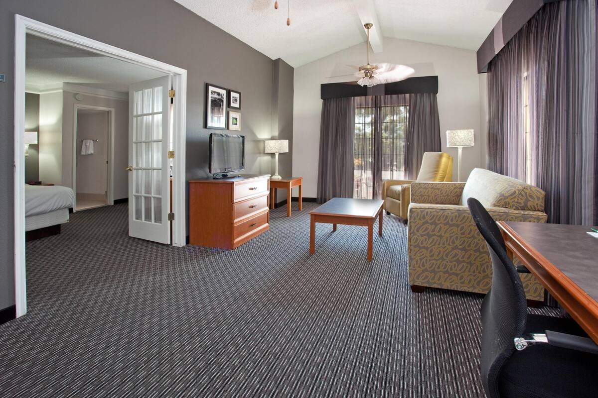 A hotel room with a bed, a desk, a chair, a television, and a window with curtains.