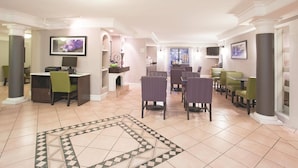 Un hall d’hôtel comprenant un espace repas, un comptoir d’accueil et un téléviseur fixé au mur.
