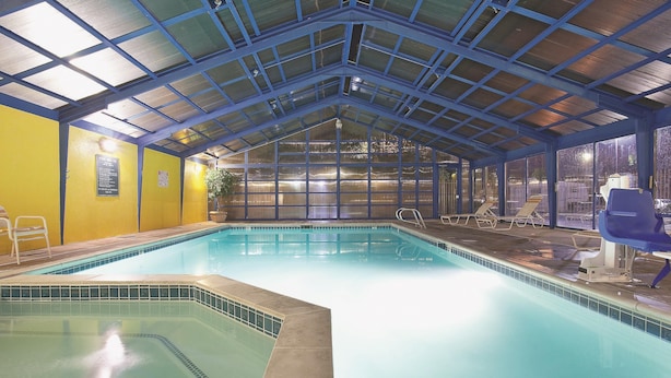 Une piscine intérieure dotée d’un toit en verre et de murs jaunes.