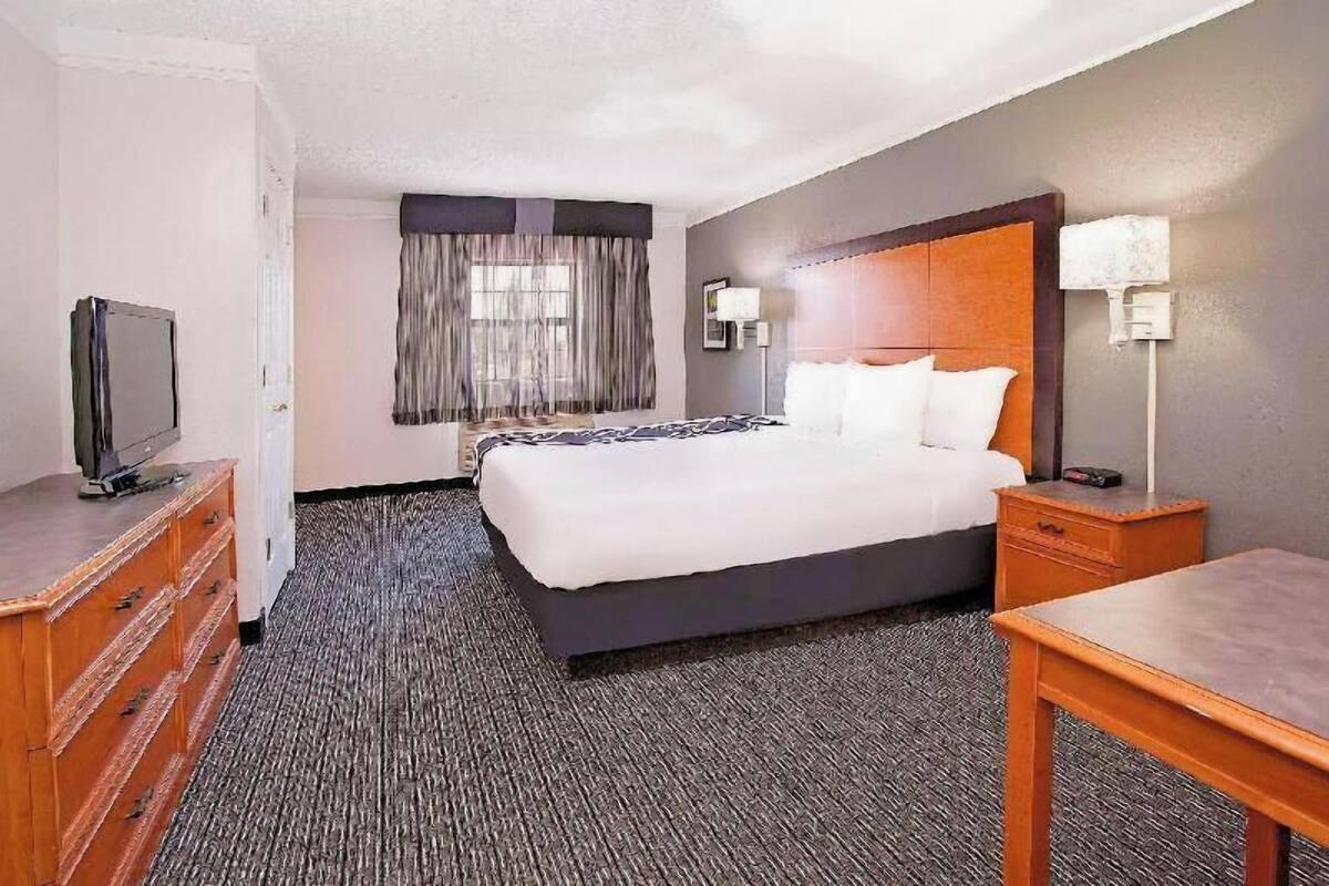 A hotel room with a bed, a television, a desk, and a lamp.