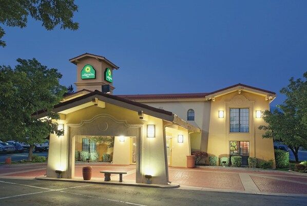 A La Quinta hotel with a well-lit entrance, a covered waiting area, and a parking lot.