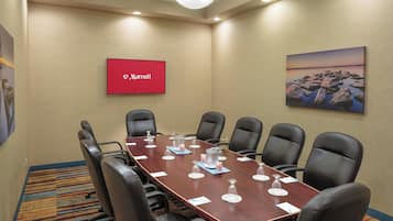 A conference room with a long table, black chairs, and a Marriott sign on the wall.