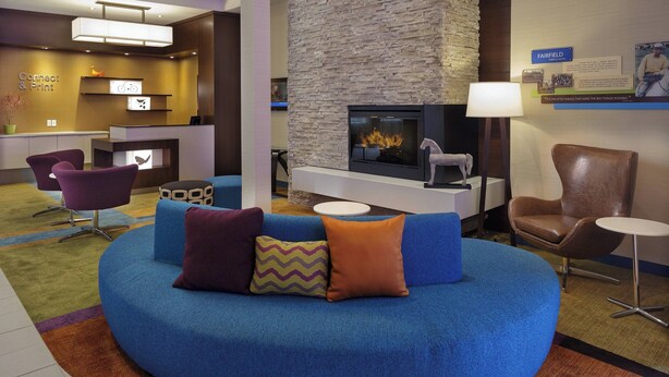 A modern lobby with a blue sofa, a fireplace, and a reception desk. - Fairfield Inn & Suites by Marriott Belleville (Belleville)