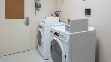 Una sala de lavandería con dos lavadoras de carga frontal, una secadora y un teléfono.