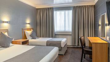 Habitación de hotel con dos camas, un escritorio y una silla.