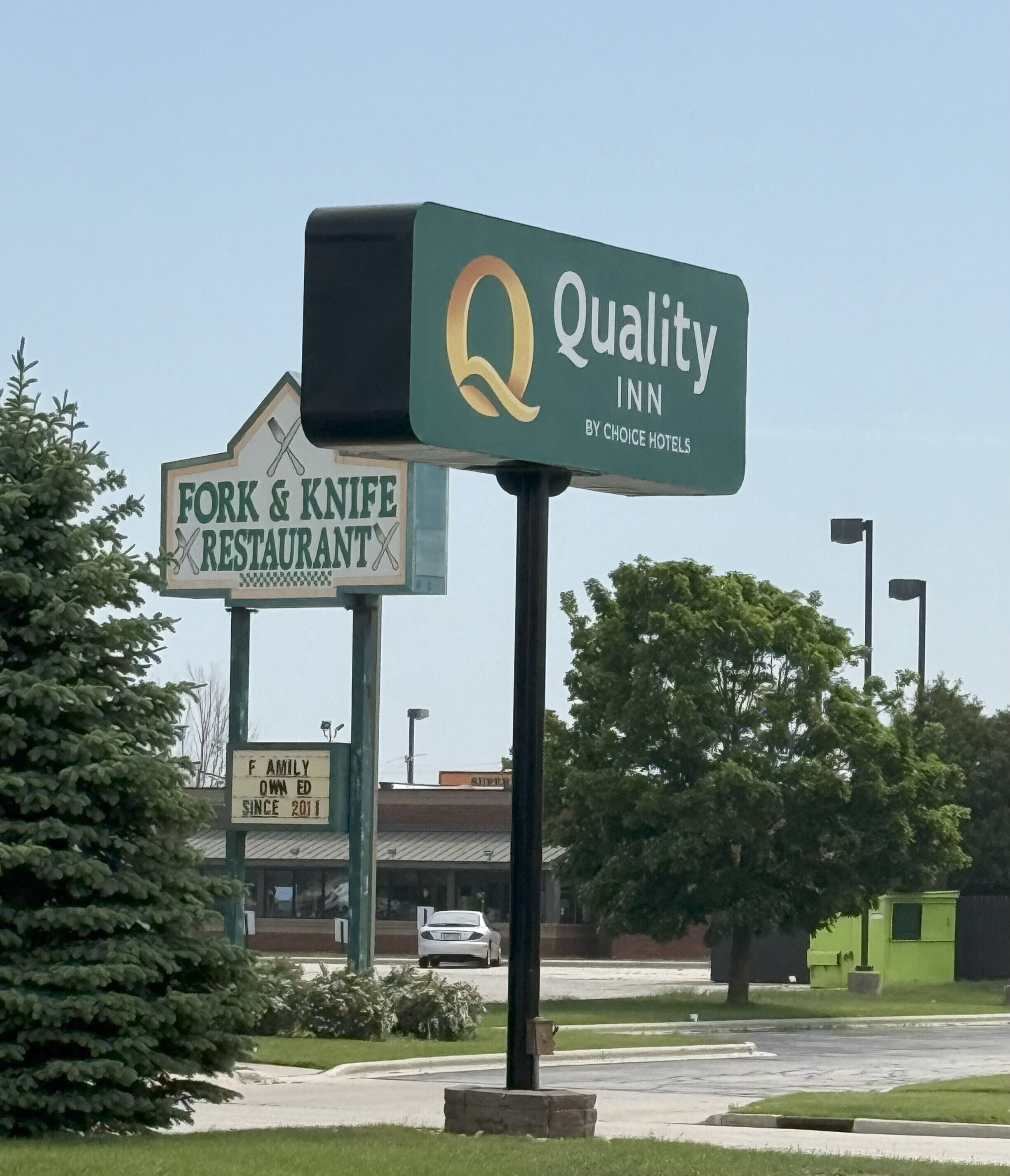 Quality Inn -hotellin kyltti, jonka alla on ravintolan kyltti, jossa on haarukka ja veitsi.