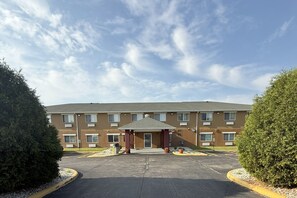 A multi-story motel with a central entrance and a covered waiting area.