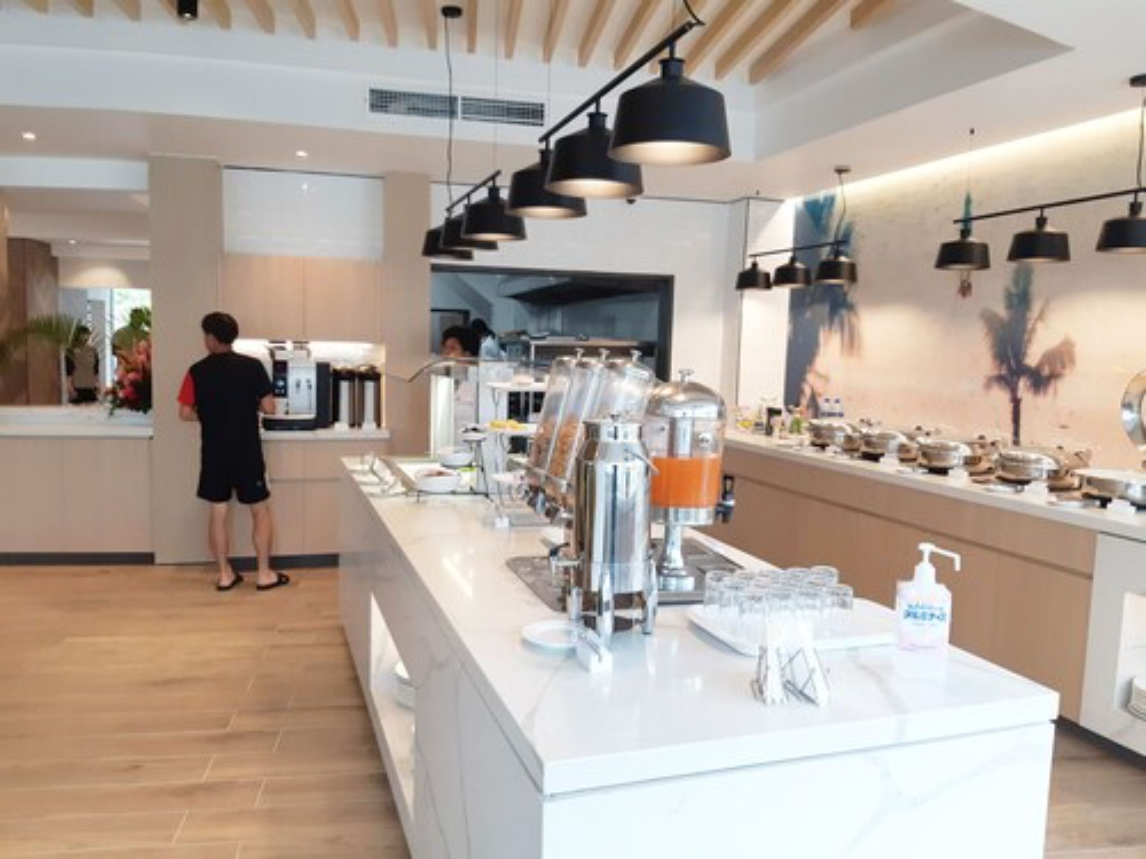 Una cafetería moderna con una barra larga, máquinas de café y diversos productos alimenticios.