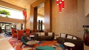 A lobby with a modern design, featuring a mix of seating options including sofas and chairs, a patterned carpet, and a brick wall. - Hilton Palm Springs Resort (Palm Springs)