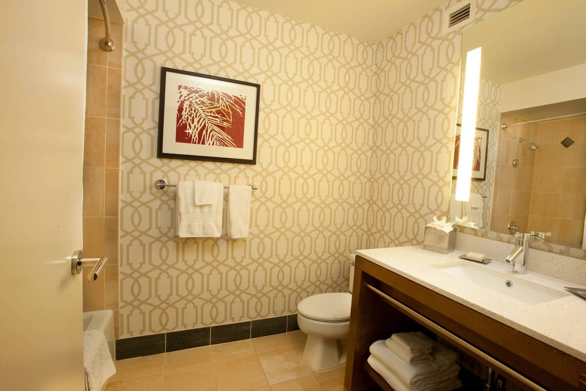 A modern bathroom with patterned walls, a toilet, a sink with a mirror, and a shower area.