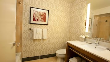 A modern bathroom with patterned walls, a toilet, a sink with a mirror, and a shower area.