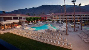 A resort with a swimming pool, lounge chairs, and palm trees. - Hilton Palm Springs Resort (Palm Springs)
