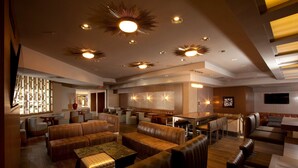 A spacious lobby with leather seating, a central bar area, and a modern ceiling design. - Hilton Palm Springs Resort (Palm Springs)