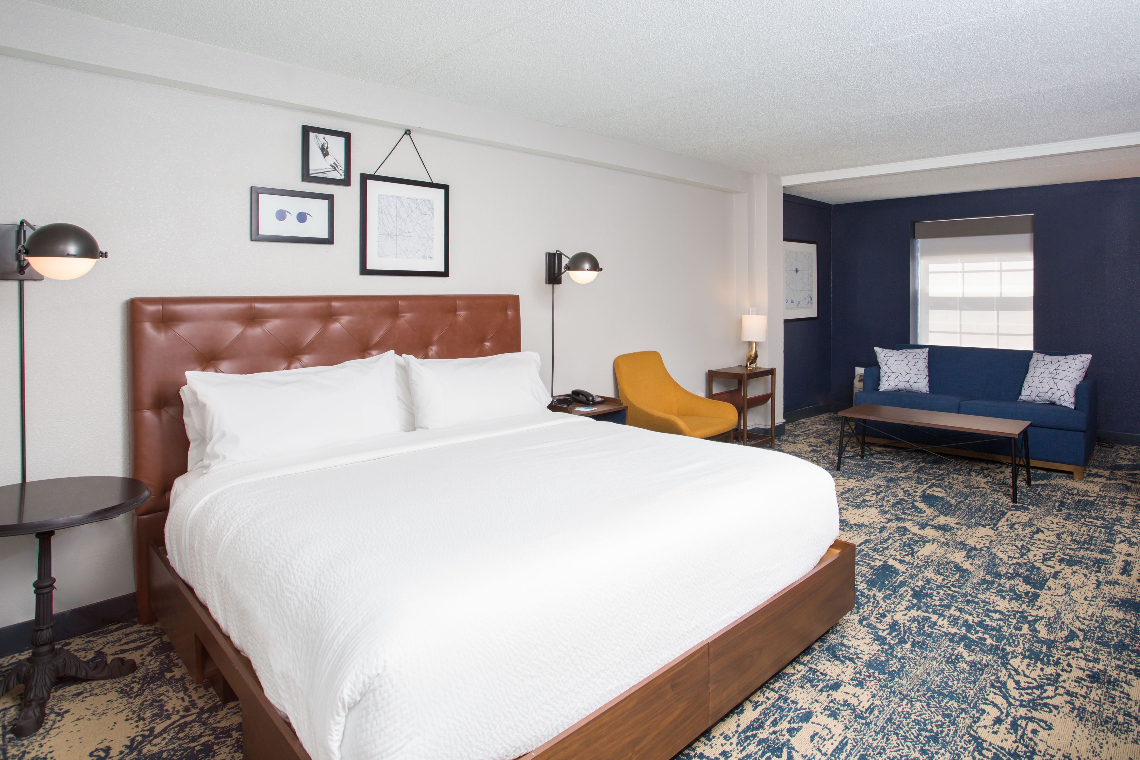 A hotel room with a large bed, a sofa, a chair, and a desk.