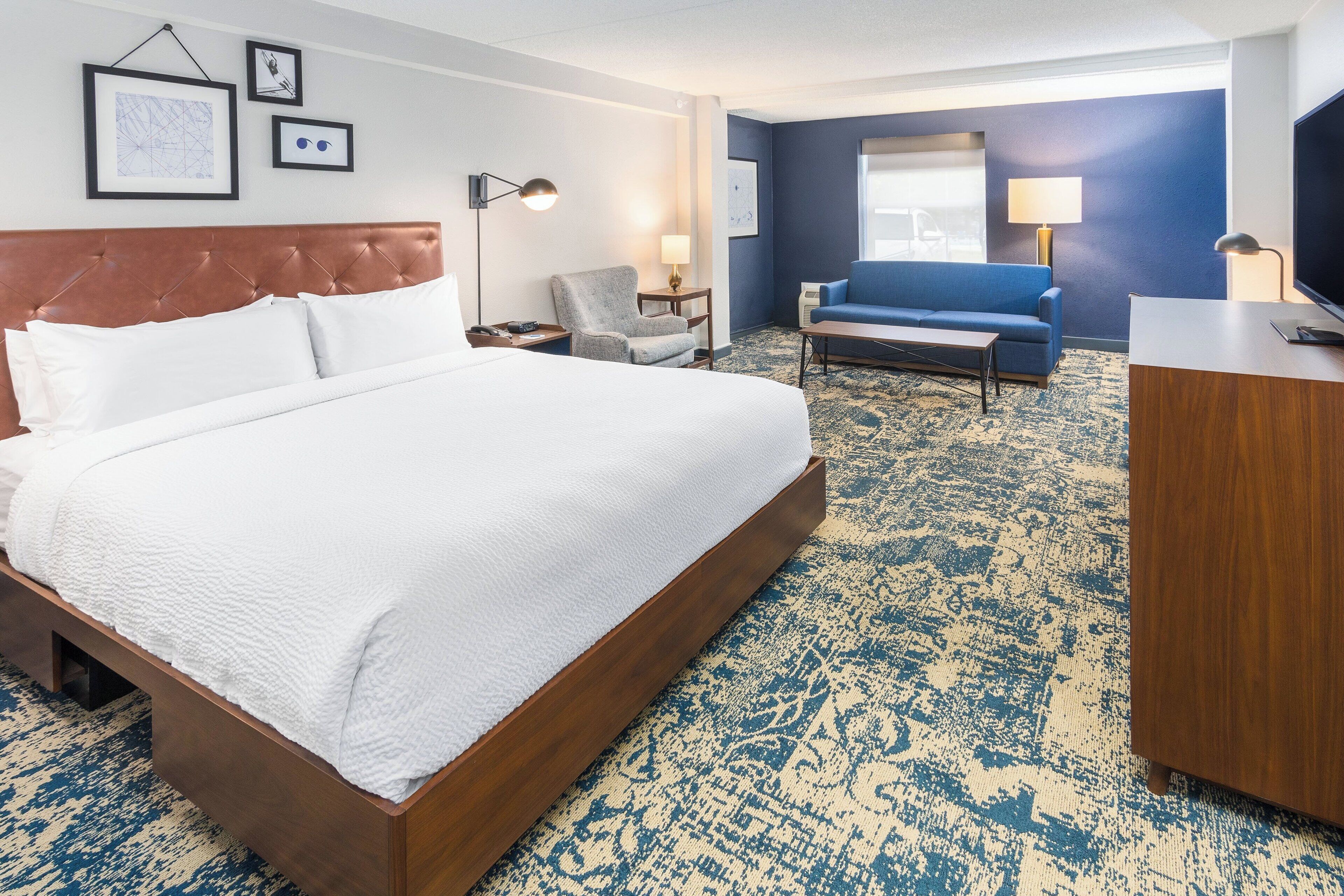 Ein Hotelzimmer mit einem großen Bett, einem blauen Sofa, einem Schreibtisch und einem Sessel.
