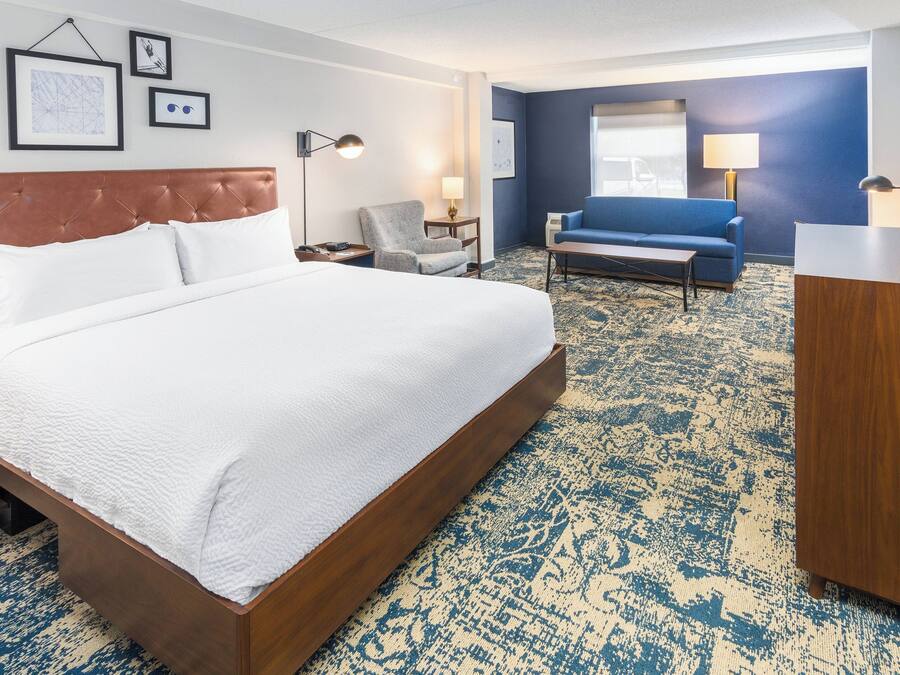 Ein Hotelzimmer mit einem großen Bett, einem blauen Sofa, einem Schreibtisch und einem Sessel.