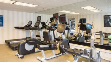 A gym with various exercise equipment, including treadmills, elliptical machines, and weight machines.