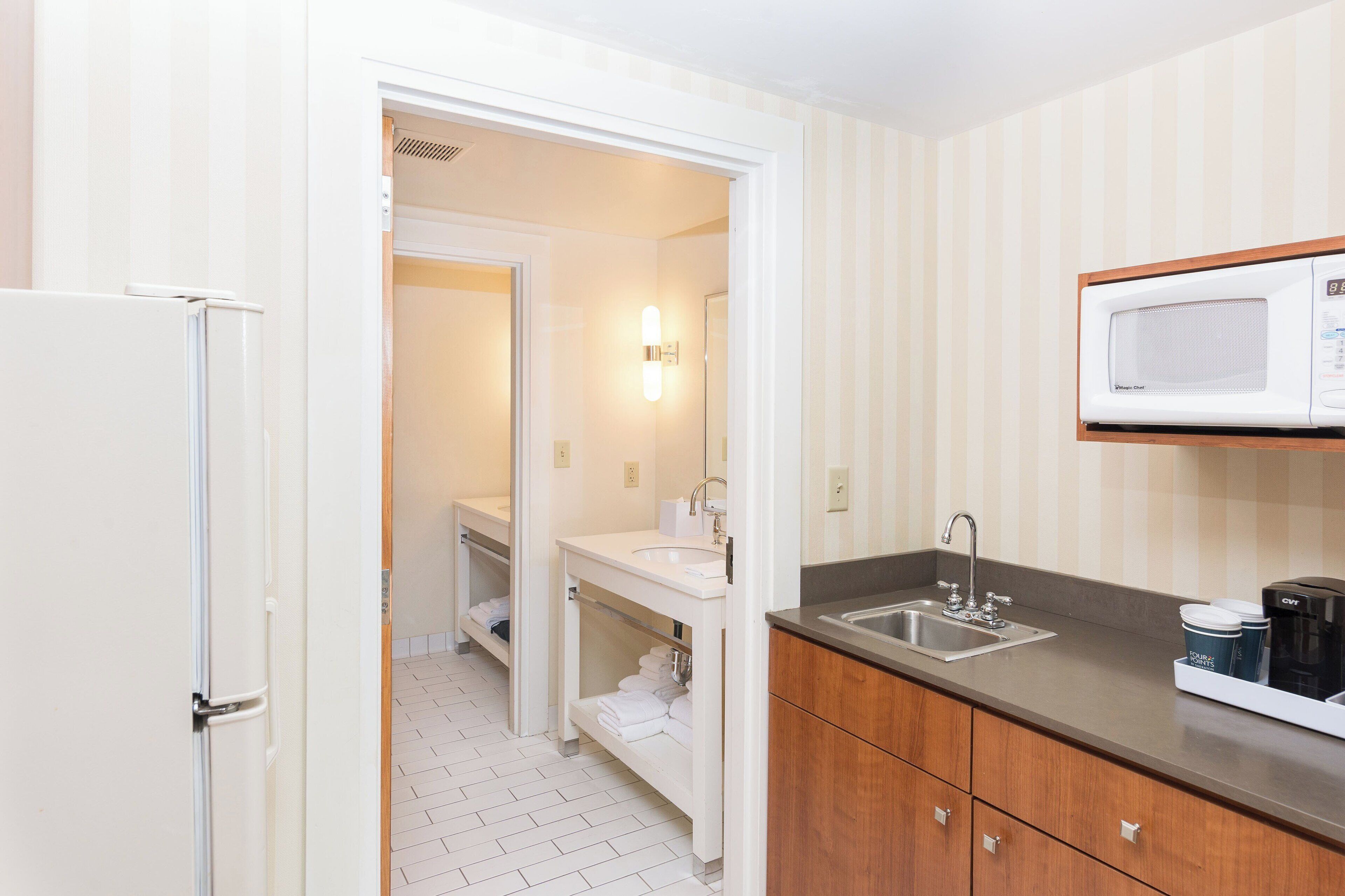 A modern bathroom with a white sink, a mirror, a shower, and a toilet.