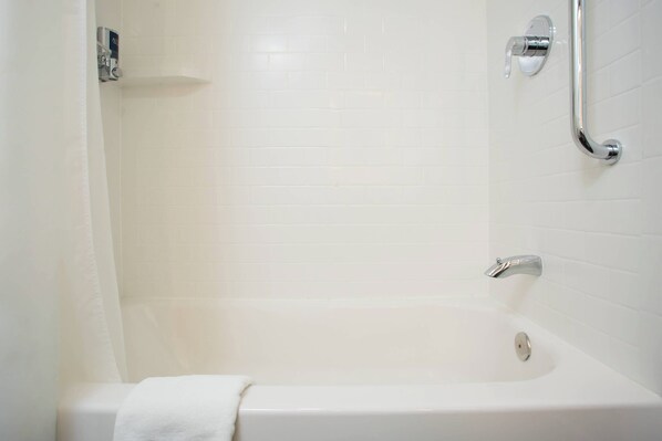 A white bathtub with a shower curtain, a handheld showerhead, and a towel on the side. - Four Points by Sheraton Eastham Cape Cod (Eastham)