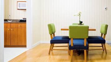 Un coin repas avec une table en bois et deux chaises recouvertes d’un tissu vert.