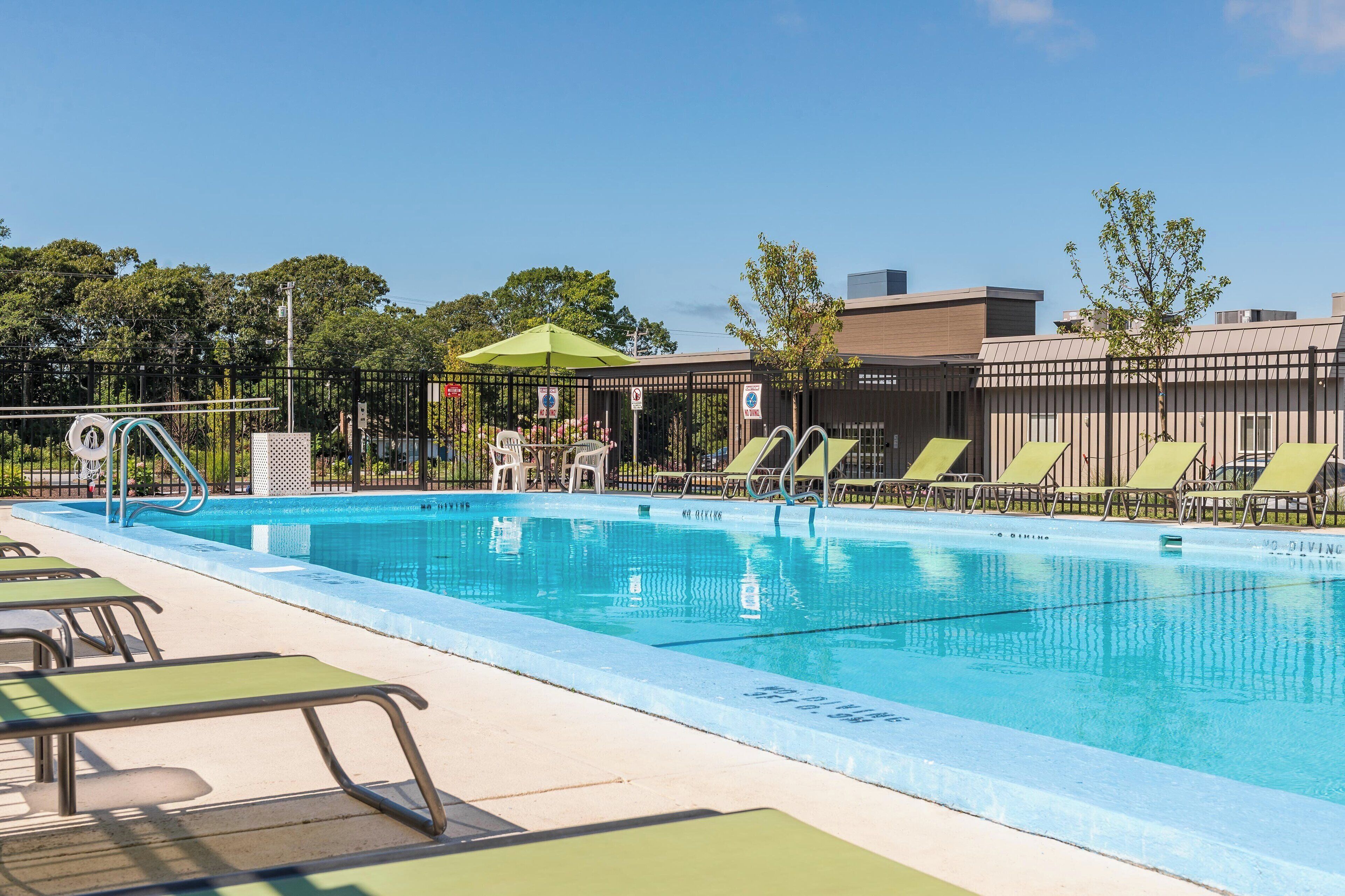 A swimming pool with lounge chairs and a covered seating area.