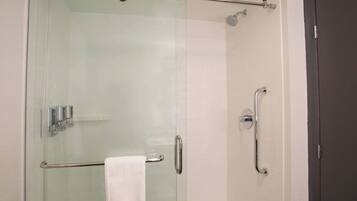 A glass-enclosed shower with a handrail, a towel rack, and a door with a handle.