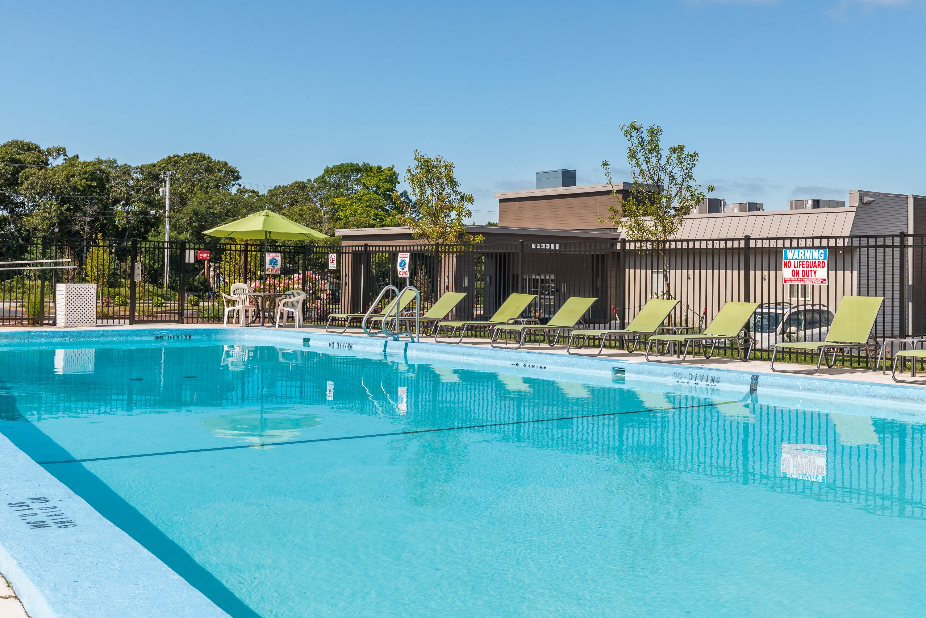 Piscina con sillas de descanso y zona sombreada.