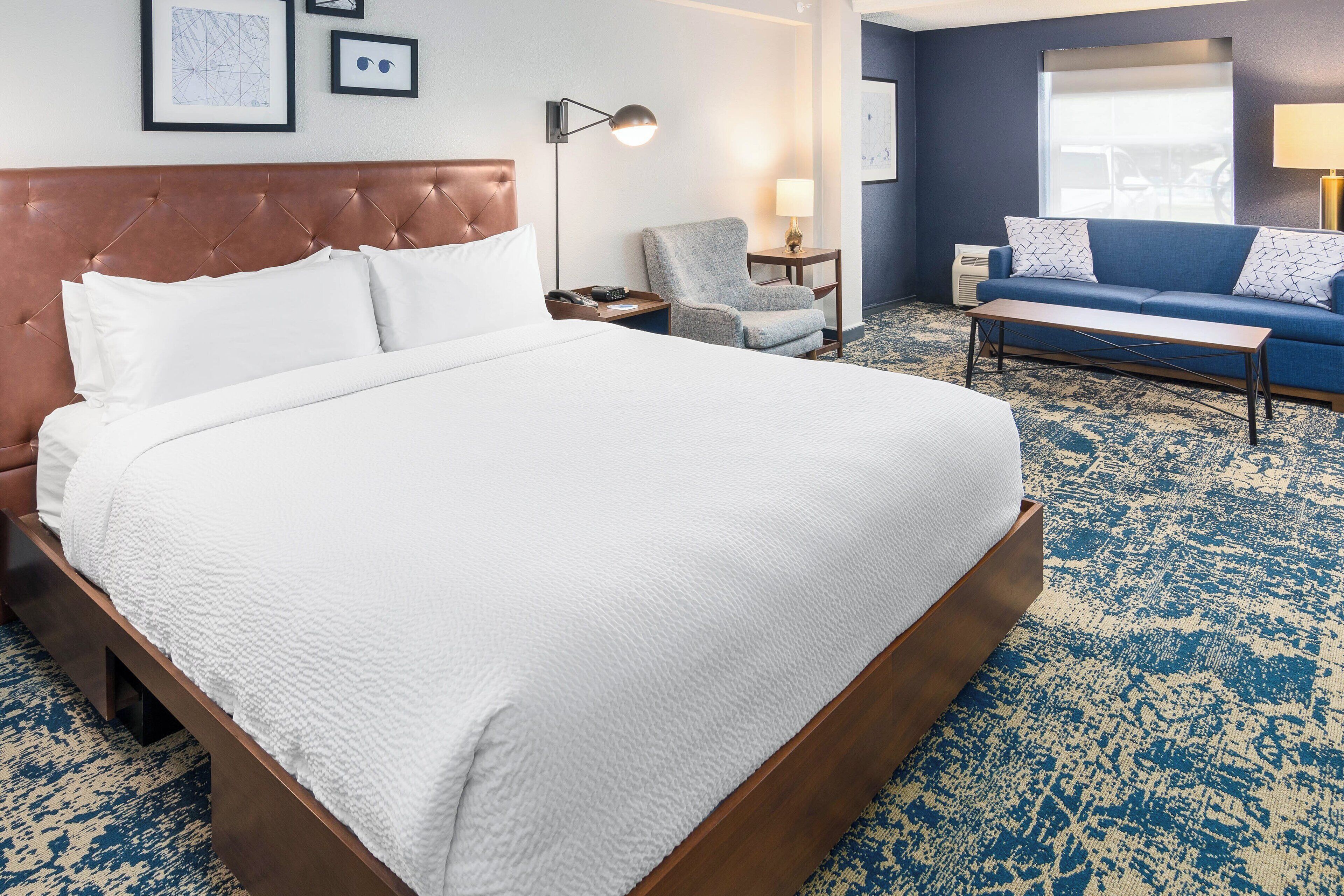 Une chambre d’hôtel avec un grand lit, un canapé, un fauteuil, un bureau et une fenêtre.