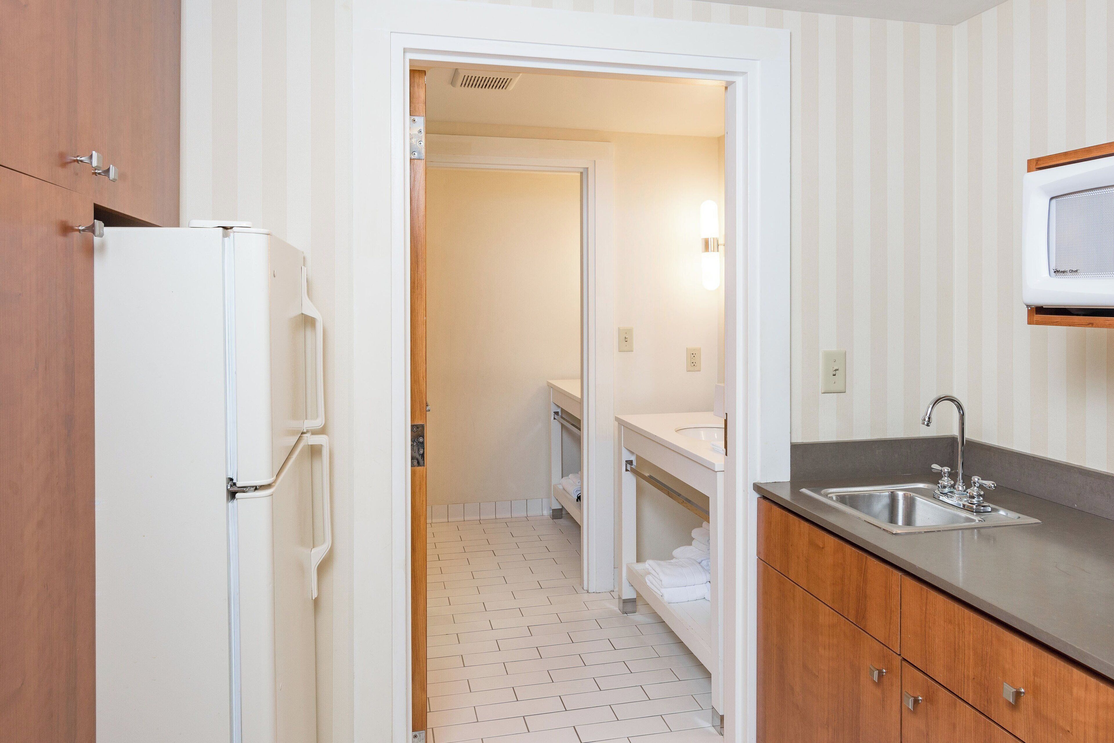 A compact kitchen with a refrigerator, a sink, and a microwave.