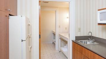 A compact kitchen with a refrigerator, a sink, and a microwave.