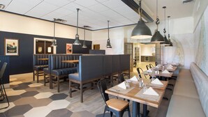 A modern restaurant with hexagonal patterned flooring, booth seating, and pendant lighting. - Four Points by Sheraton Eastham Cape Cod (Eastham)