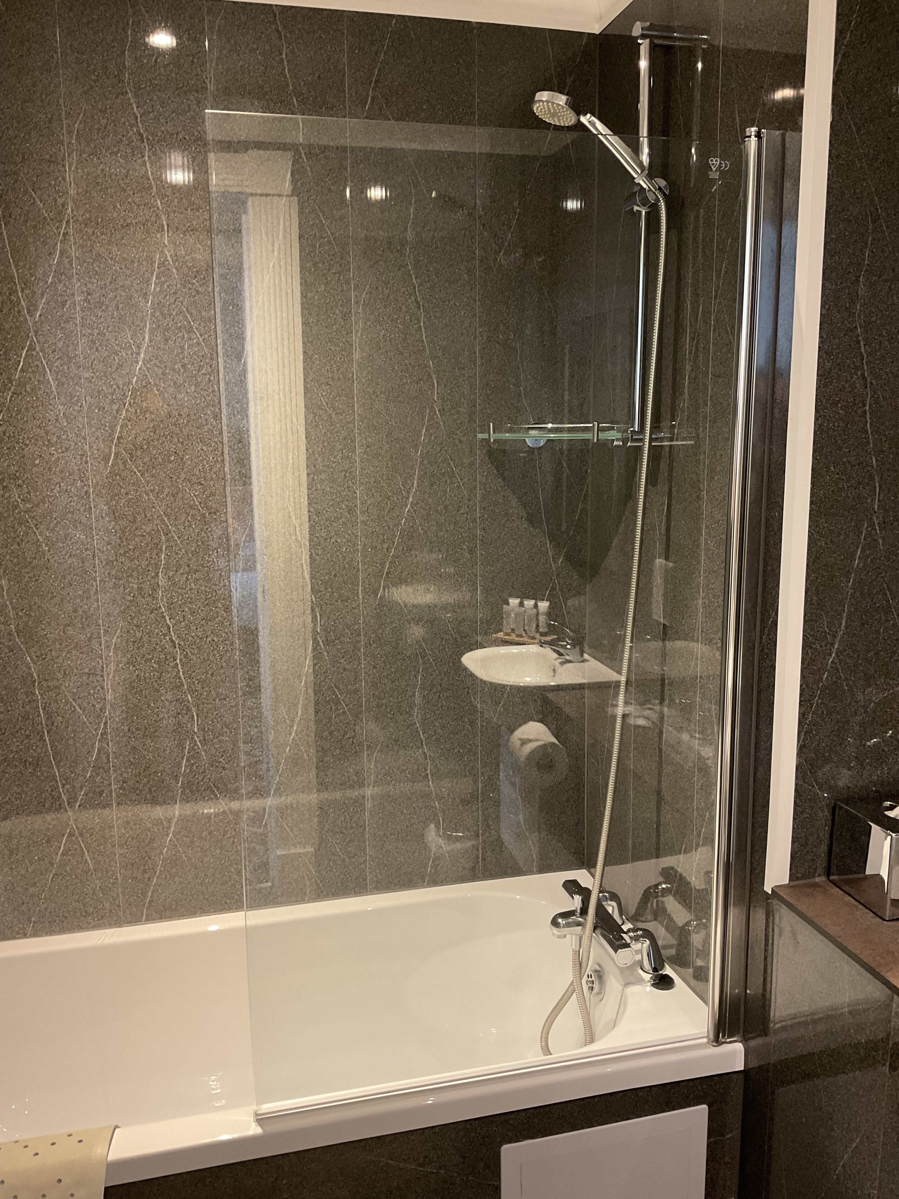 Ein modernes Badezimmer mit einer gläsernen Dusche, einer weißen Badewanne und einem Waschbecken.