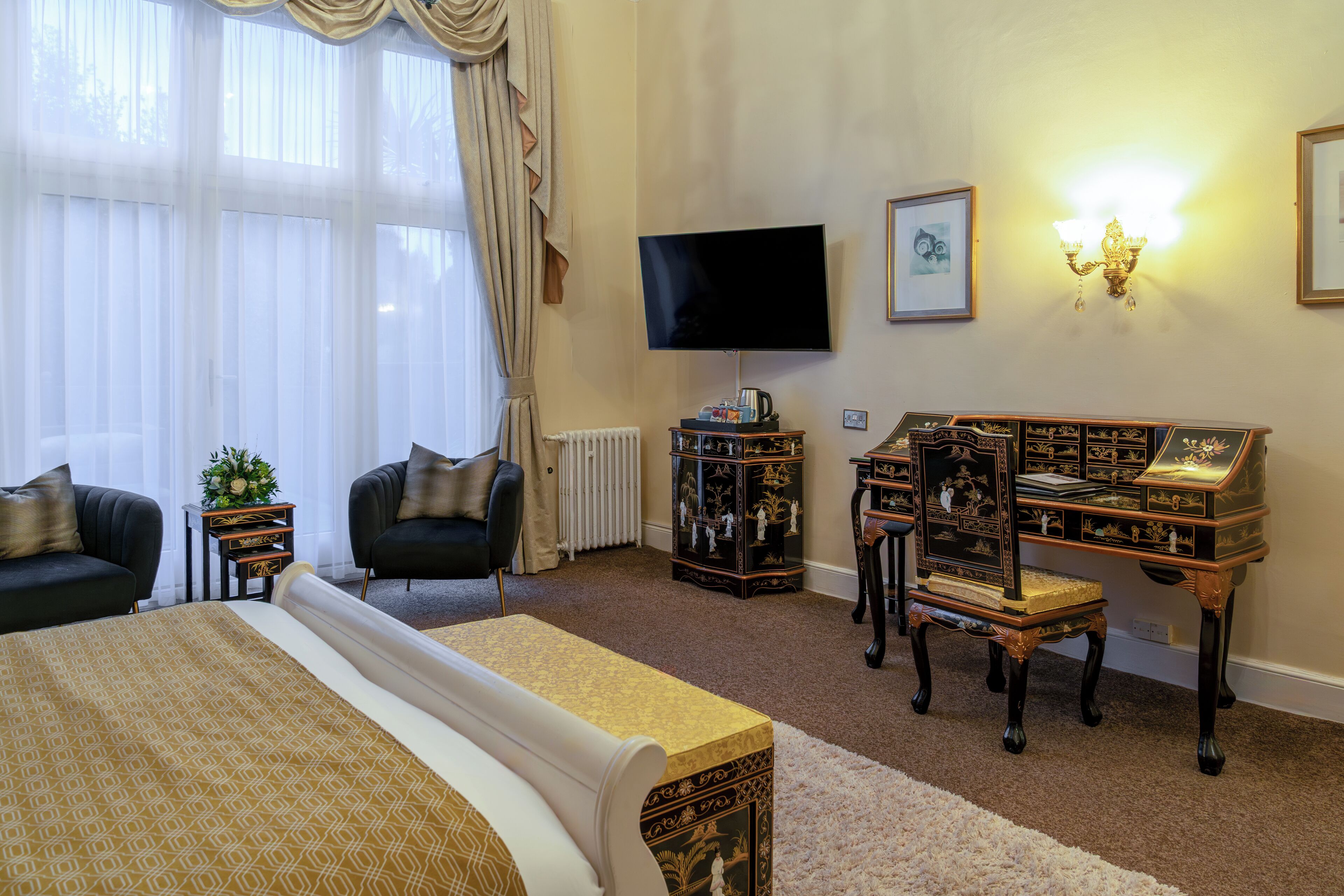 Une chambre d’hôtel avec un grand lit, un bureau avec un ordinateur, une chaise, une télévision et une fenêtre avec des rideaux.