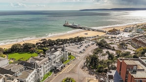 A coastal town with a prominent pier extending into the sea, a sandy beach, and a mix of residential and commercial buildings.