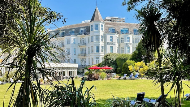 A hotel with a large, white building featuring multiple balconies and a prominent tower.
