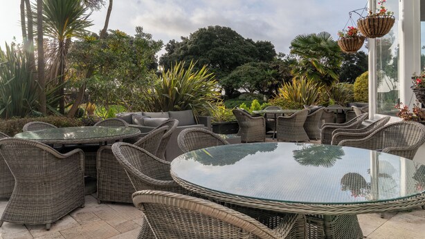 An outdoor patio with wicker furniture, a glass table, and potted plants. - Royal Bath Hotel (Bournemouth)